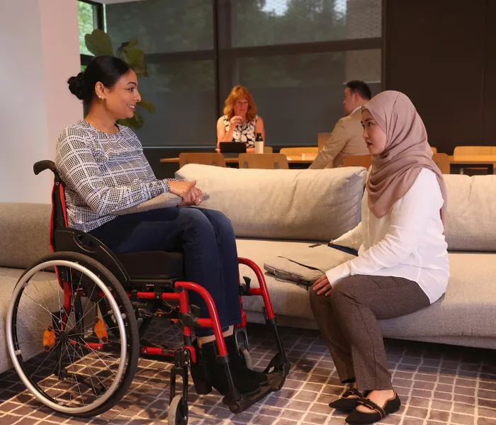 Disabled woman in wheelchair talking with woman wearing headscarf