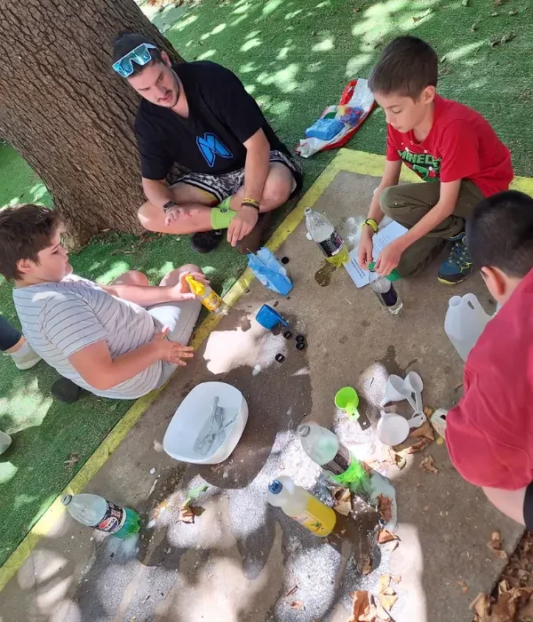 Group of young children outside doing an experiment in the park with support worker