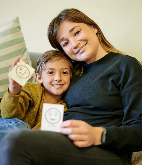 Mother sitting with son, holding up cards that show different emotions